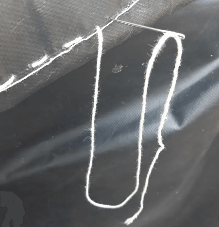 Sewing a tarp with a needle and string
